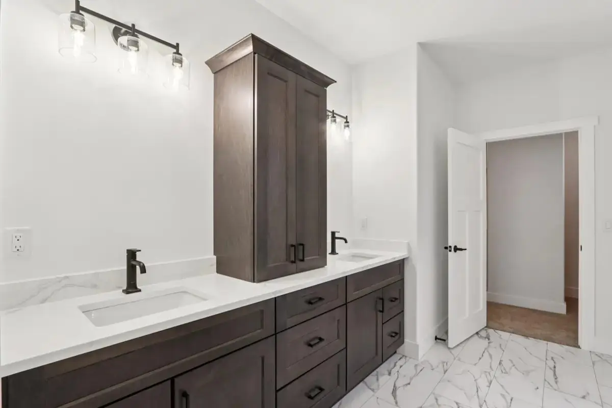 Bathroom with a dark double vanity, tower cabinet and marble-look tile floor