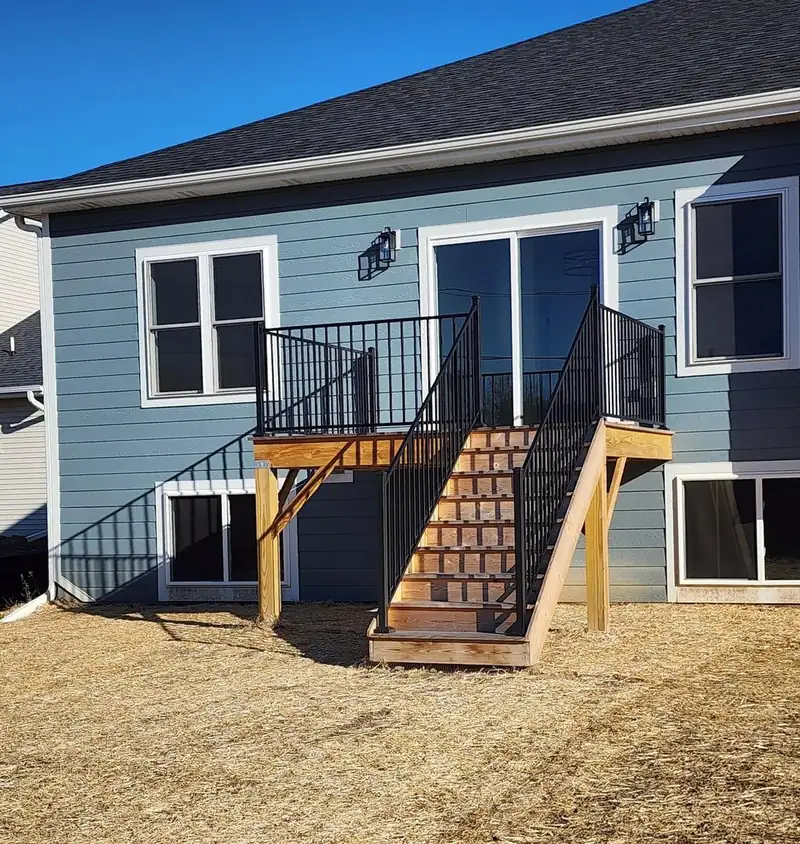 Back of the house showing the walkout, with the exterior stair framed and railed