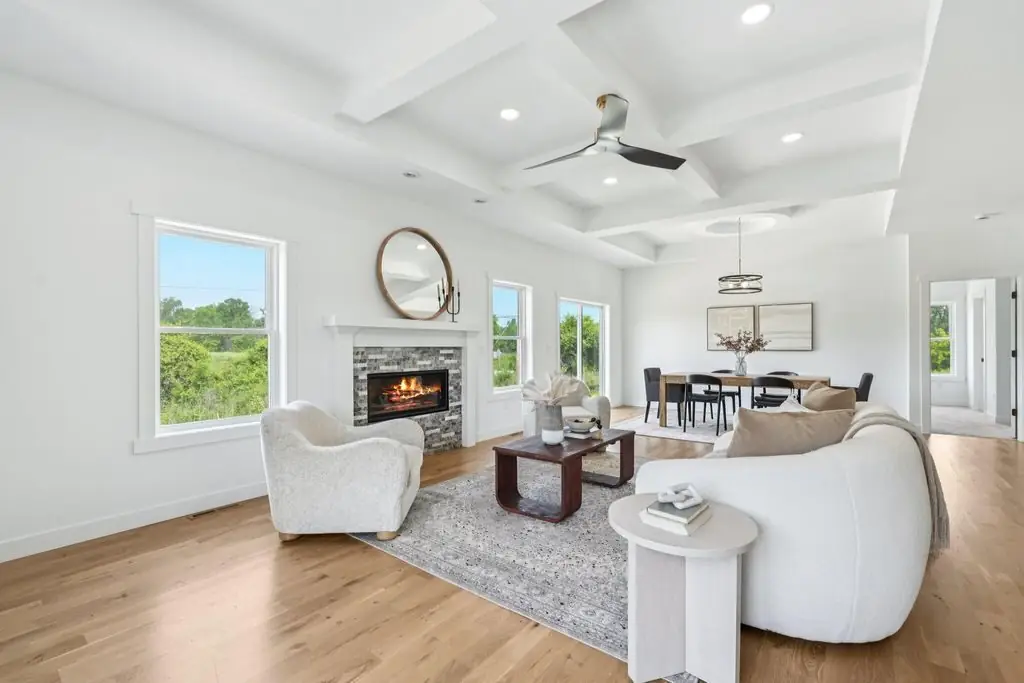 Living room with a coffered ceiling, stone fireplace and windows facing open country