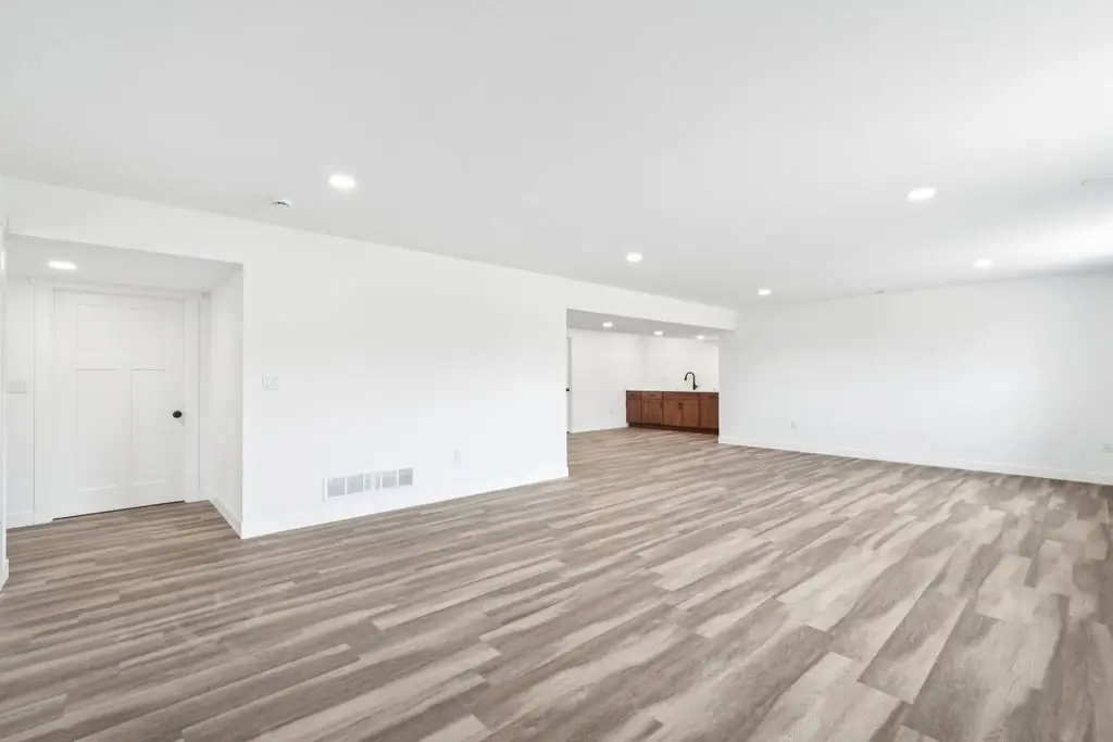 Finished lower level, open plan with plank flooring and recessed lighting